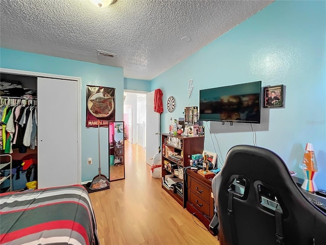 bedroom with a textured ceiling, a closet, and light hardwood / wood-style floors