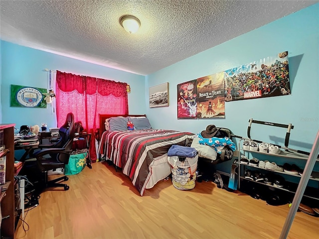 bedroom with a textured ceiling and wood-type flooring