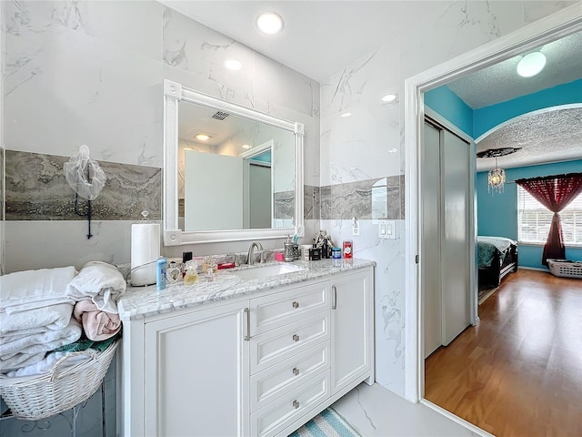 bathroom with tile walls, a textured ceiling, vanity, and hardwood / wood-style flooring