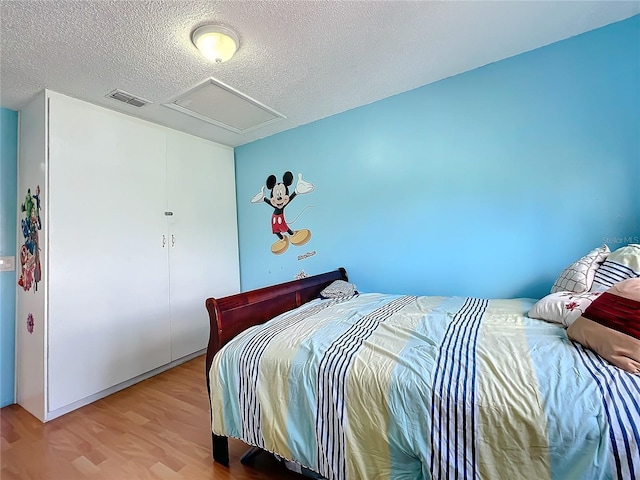 bedroom featuring a textured ceiling and light hardwood / wood-style flooring