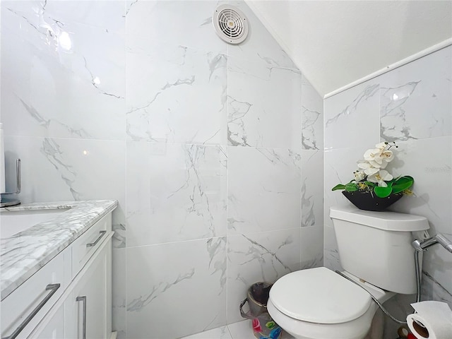 bathroom with toilet, vanity, and lofted ceiling