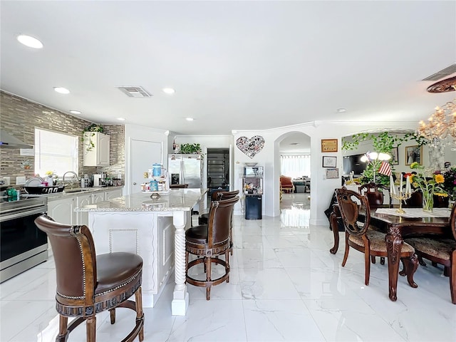 kitchen with light stone counters, a healthy amount of sunlight, a center island, appliances with stainless steel finishes, and sink