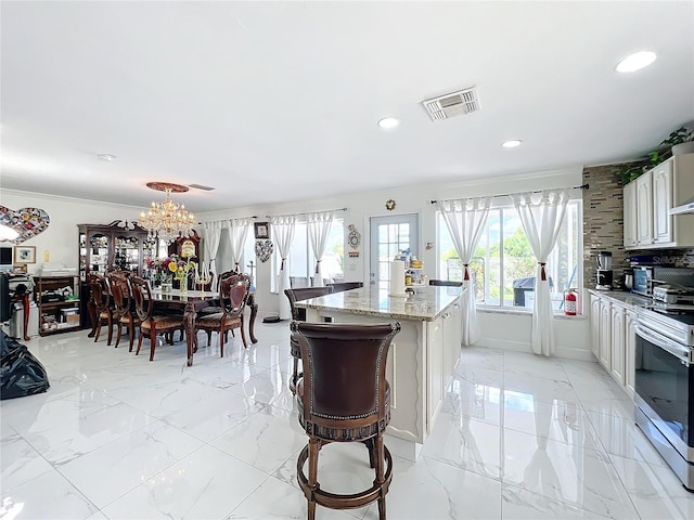 kitchen with light stone counters, a center island, electric range, an inviting chandelier, and white cabinets