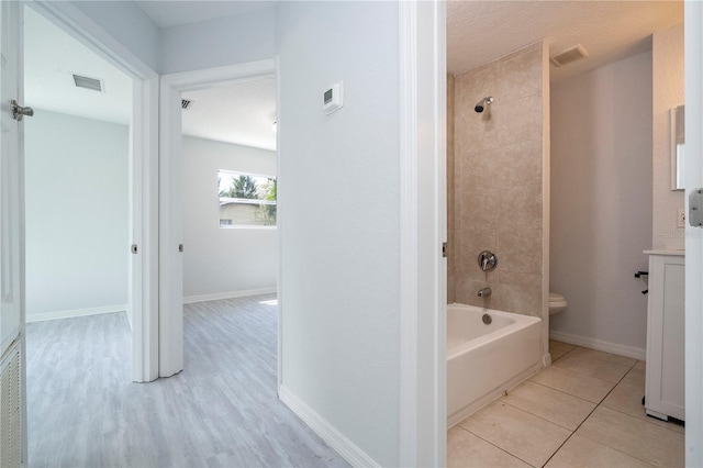 full bathroom with vanity, tiled shower / bath combo, toilet, and tile patterned floors