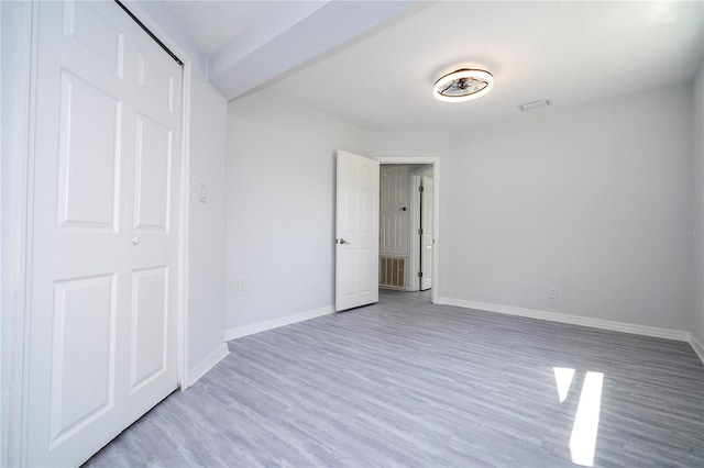 unfurnished bedroom featuring light hardwood / wood-style flooring and a closet