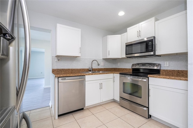 kitchen featuring tasteful backsplash, appliances with stainless steel finishes, sink, white cabinetry, and dark stone counters