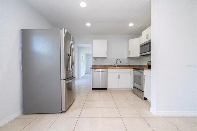 kitchen with stainless steel appliances, sink, light tile patterned floors, white cabinets, and a textured ceiling