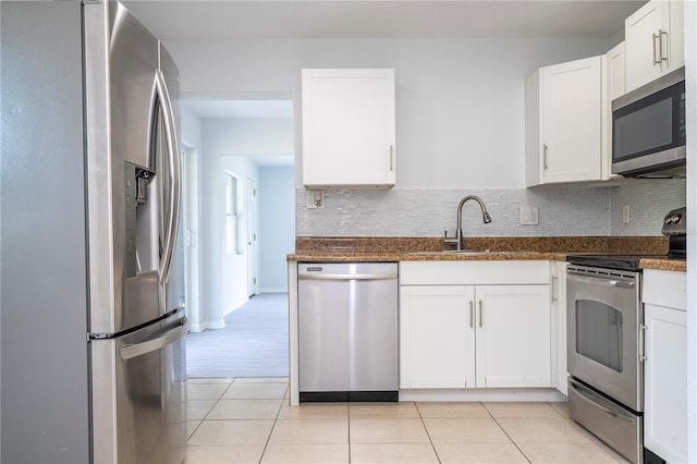 kitchen with appliances with stainless steel finishes, sink, white cabinetry, decorative backsplash, and light tile patterned floors