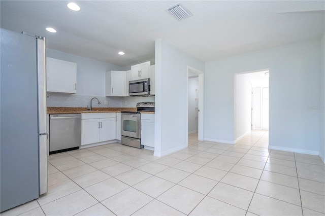 kitchen with appliances with stainless steel finishes, white cabinets, sink, and light tile patterned floors