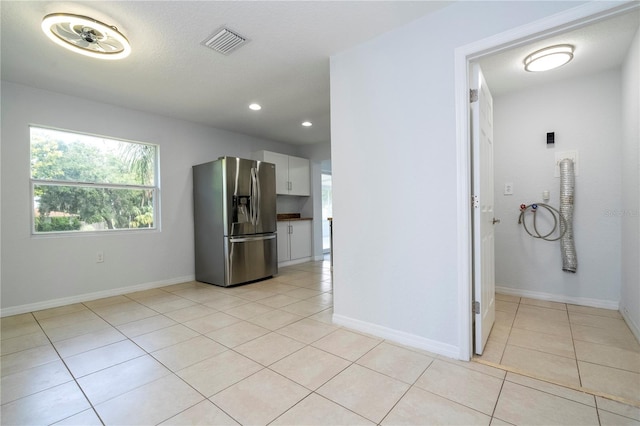 interior space featuring white cabinetry, stainless steel refrigerator with ice dispenser, and light tile patterned floors