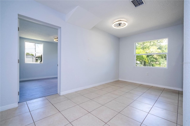 unfurnished room with a textured ceiling and light wood-type flooring