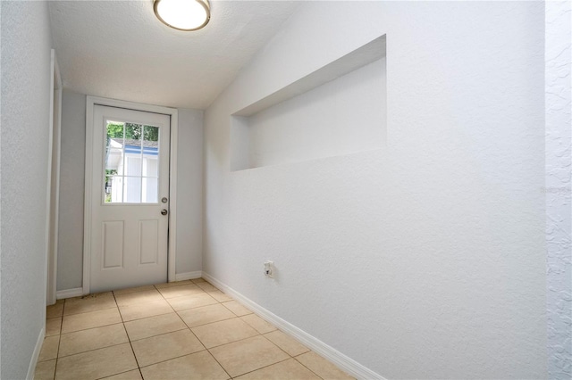 doorway with light tile patterned floors, a textured ceiling, and vaulted ceiling