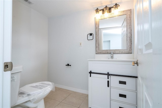 bathroom with toilet, vanity, and tile patterned floors