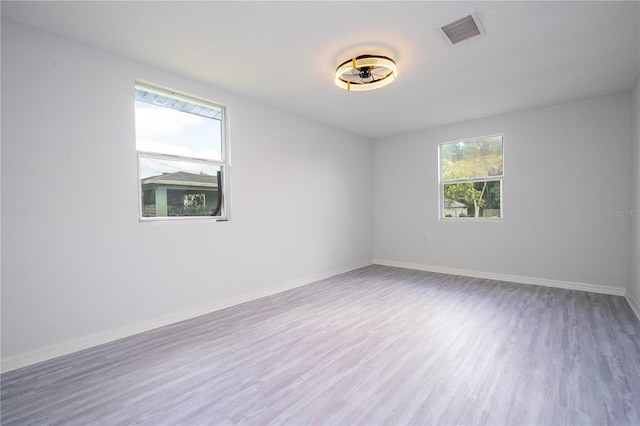 unfurnished room with hardwood / wood-style flooring and a healthy amount of sunlight