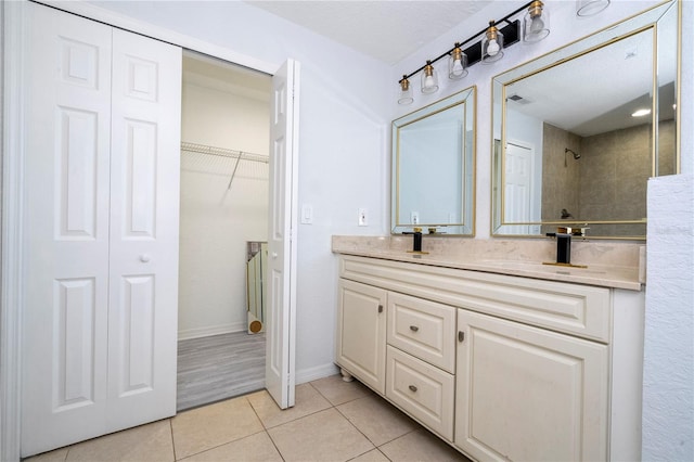 bathroom featuring vanity, a tile shower, a textured ceiling, and tile patterned flooring