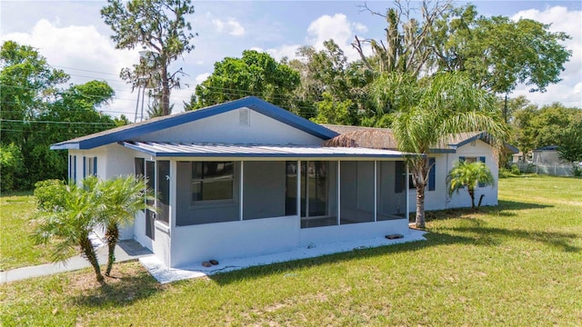 back of property with a yard and a sunroom