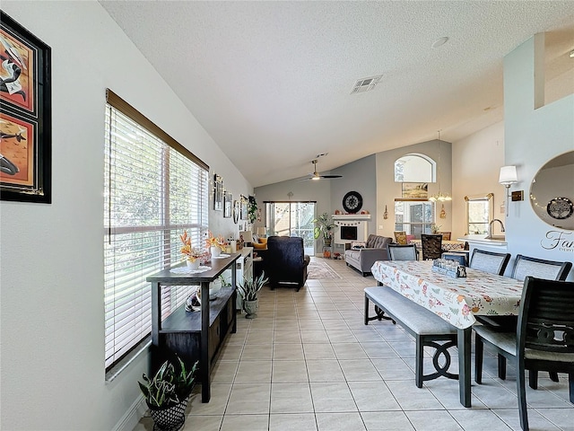 dining area with lofted ceiling, ceiling fan, light tile patterned flooring, and a textured ceiling