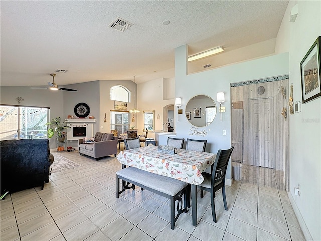 tiled dining area with a textured ceiling, vaulted ceiling, and ceiling fan