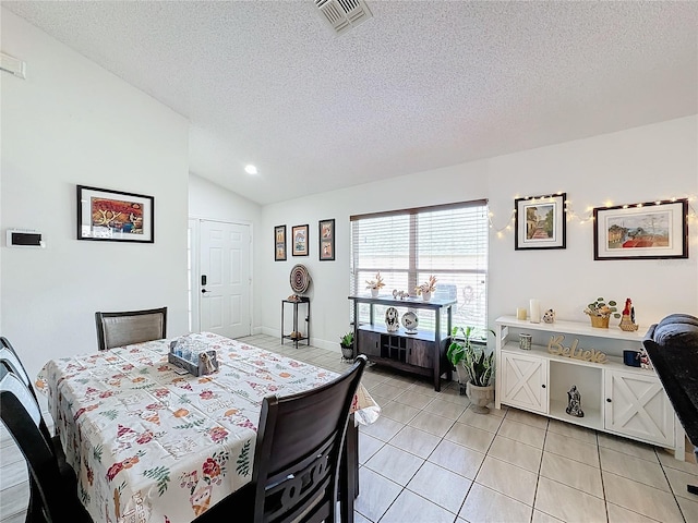 tiled dining area featuring a textured ceiling and vaulted ceiling