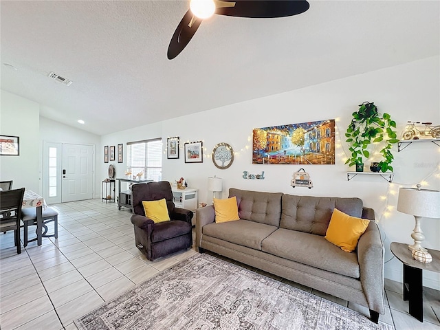 living room featuring ceiling fan, light tile patterned floors, a textured ceiling, and vaulted ceiling