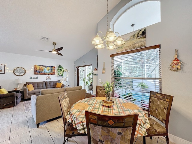 dining area featuring ceiling fan with notable chandelier, lofted ceiling, and light tile patterned floors