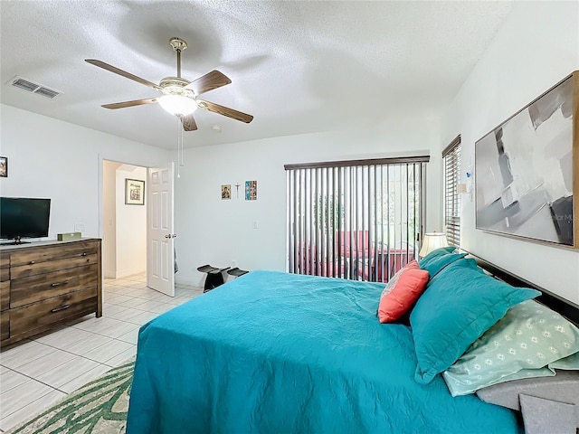 bedroom with ceiling fan, light tile patterned flooring, and a textured ceiling