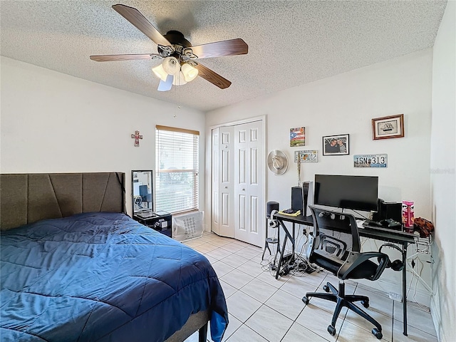 bedroom with a closet, ceiling fan, light tile patterned flooring, and a textured ceiling