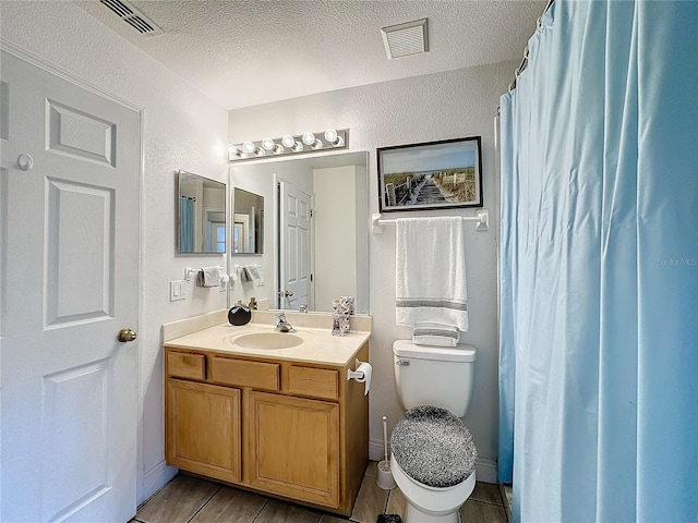 bathroom with vanity, toilet, and a textured ceiling