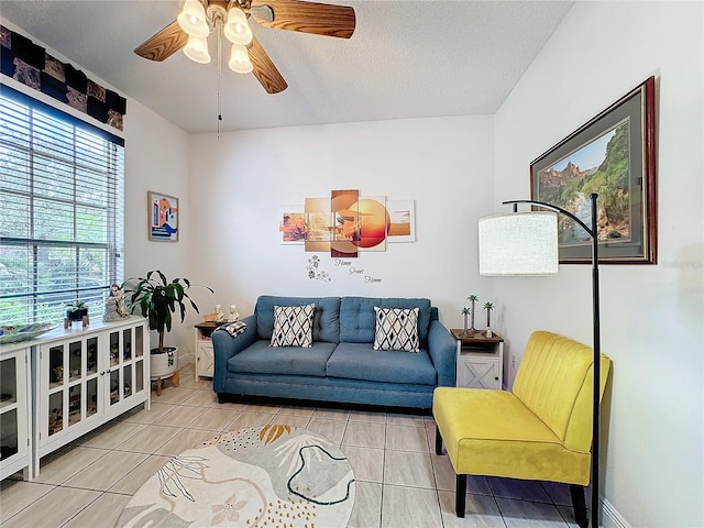 living room featuring a textured ceiling, light tile patterned floors, and ceiling fan