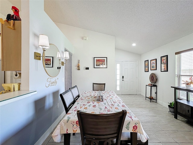 tiled dining space with a textured ceiling and lofted ceiling