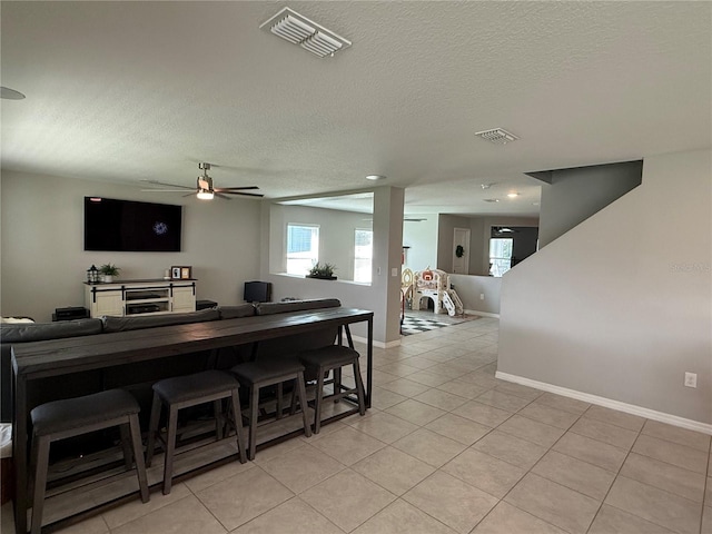 interior space with ceiling fan, light tile patterned floors, and a textured ceiling