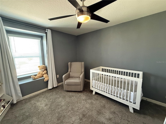 carpeted bedroom with a textured ceiling, ceiling fan, and a nursery area