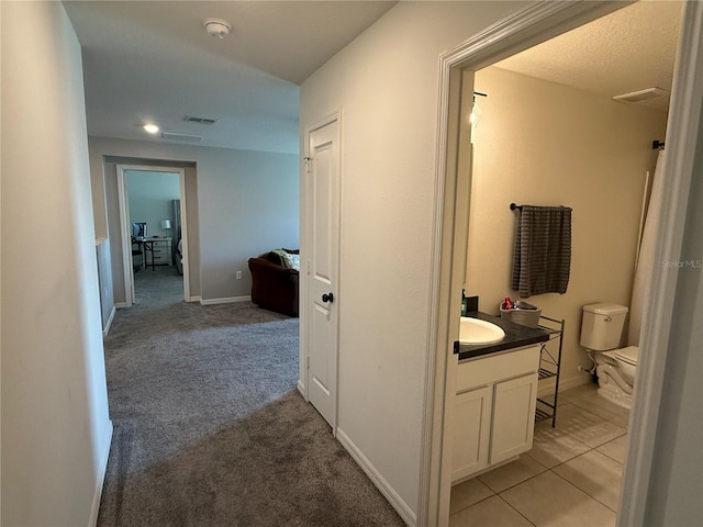 corridor featuring sink and light colored carpet