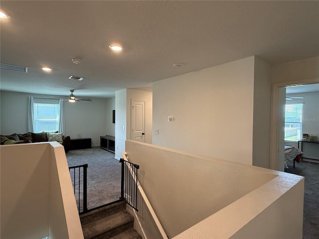 stairs with ceiling fan and carpet