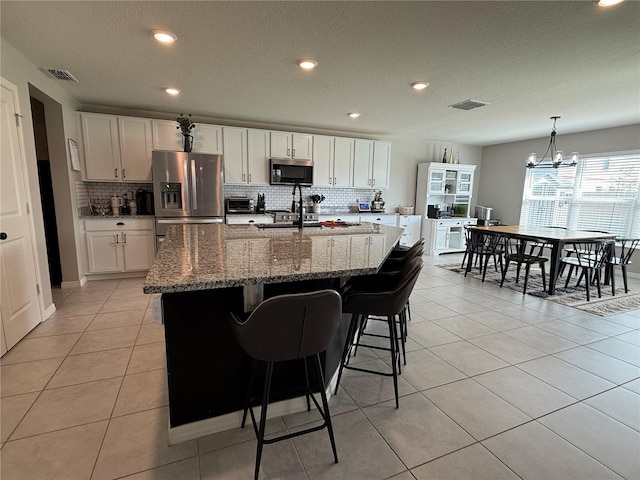 2346 Upland Ln, Apopka, FL 32712 - kitchen with appliances with stainless steel finishes, backsplash, white cabinetry, a chandelier, and a center island with sink