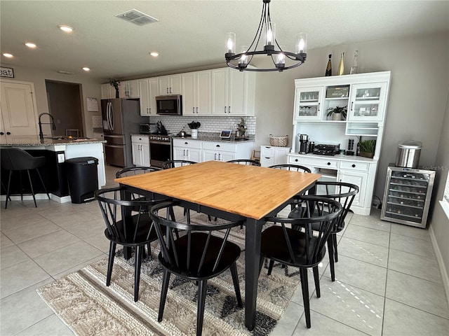 dining area featuring sink, a chandelier, wine cooler, and light tile patterned flooring