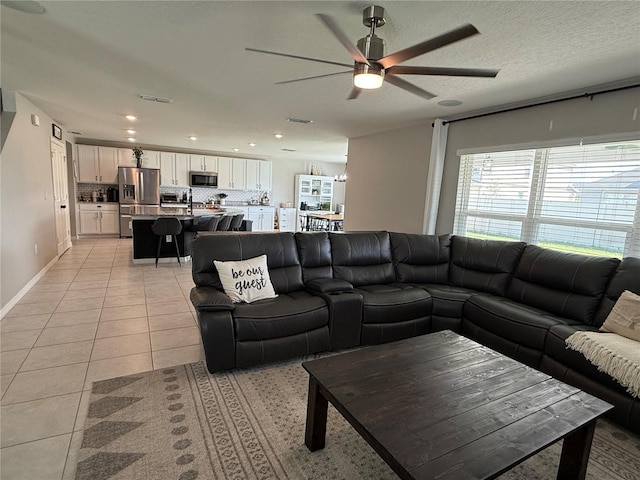 tiled living room featuring ceiling fan and a textured ceiling