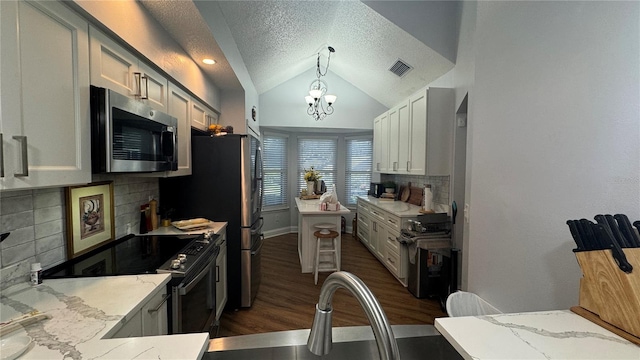 kitchen with appliances with stainless steel finishes, light stone counters, tasteful backsplash, decorative light fixtures, and a chandelier