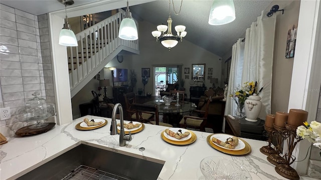 kitchen with a chandelier, a textured ceiling, light stone counters, sink, and lofted ceiling