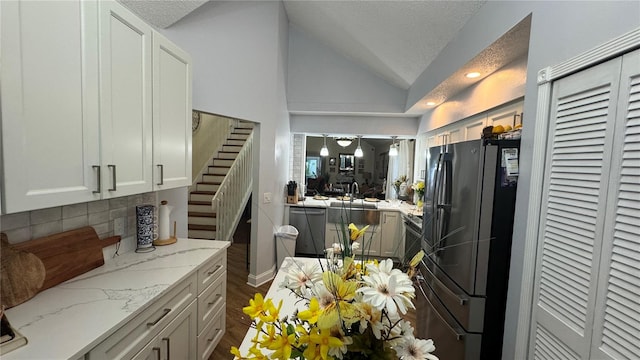 kitchen featuring a textured ceiling, black fridge, white cabinetry, lofted ceiling, and stainless steel dishwasher