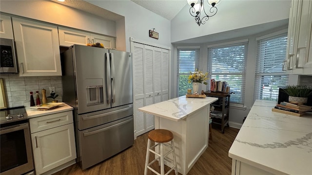 kitchen with a kitchen island, dark hardwood / wood-style flooring, stainless steel appliances, and light stone counters