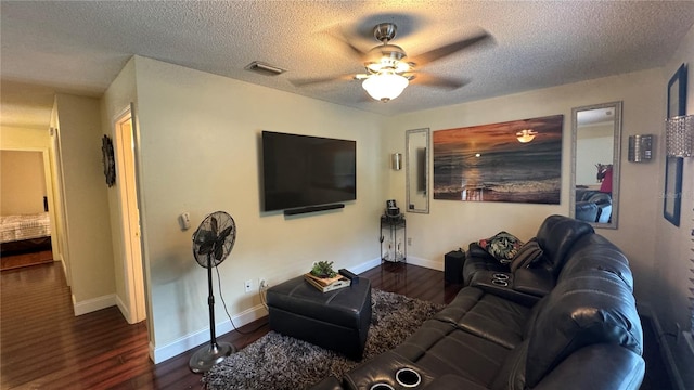 living room with ceiling fan, a textured ceiling, and dark wood-type flooring