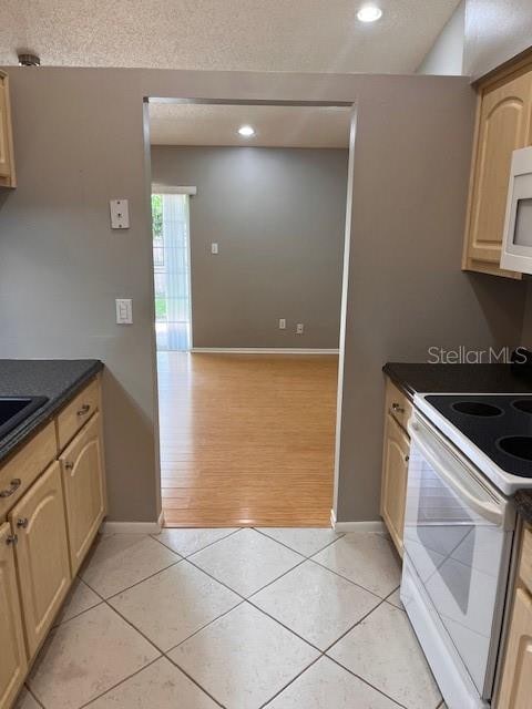 kitchen with light hardwood / wood-style floors, light brown cabinetry, and white appliances