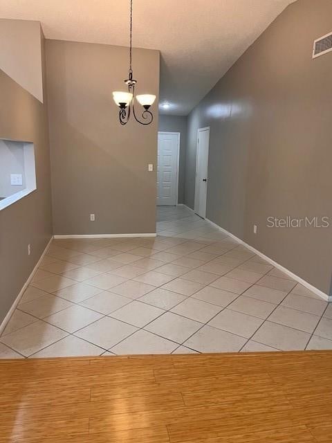 unfurnished room featuring an inviting chandelier, vaulted ceiling, and light hardwood / wood-style floors