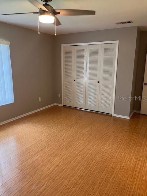 unfurnished bedroom featuring a closet, light wood-type flooring, and ceiling fan