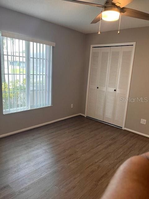 unfurnished bedroom with dark wood-type flooring, a closet, and ceiling fan