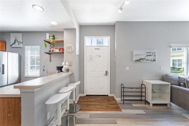 entrance foyer featuring light wood-type flooring, a textured ceiling, and sink