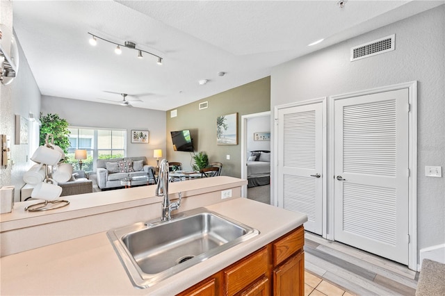 kitchen featuring ceiling fan, a textured ceiling, light wood-type flooring, and sink