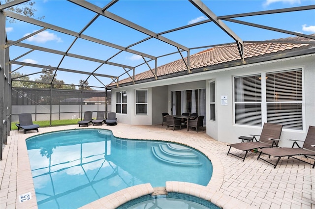 view of pool featuring a patio area, glass enclosure, and an in ground hot tub