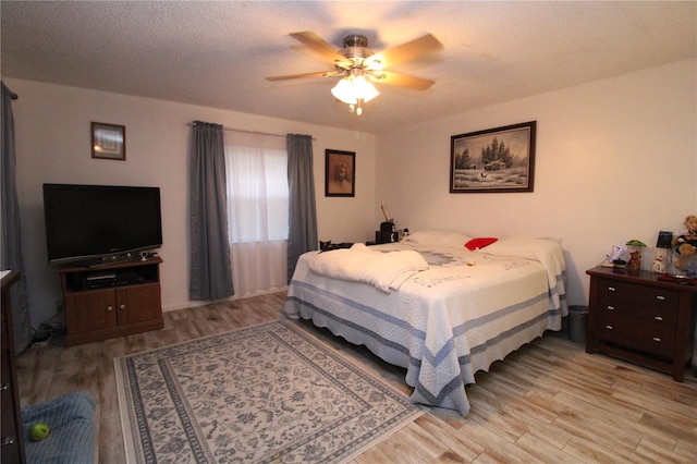 bedroom with ceiling fan, a textured ceiling, and light wood-type flooring